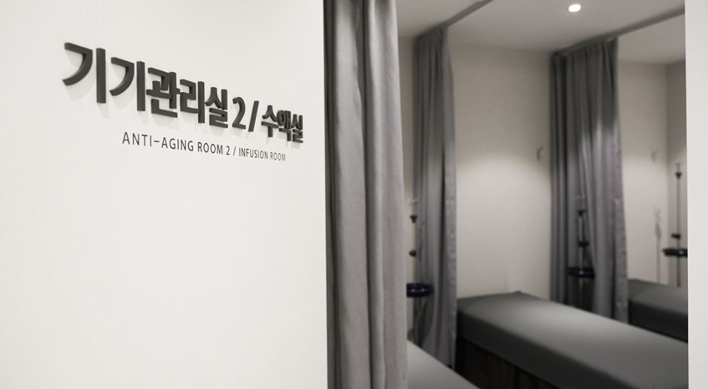 기기관리실 2 및 수액실 입구 표지판과 커튼 너머 수액 침대가 보이는 실버라이닝의원 공간